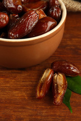 Dried dates in bowl on wooden background