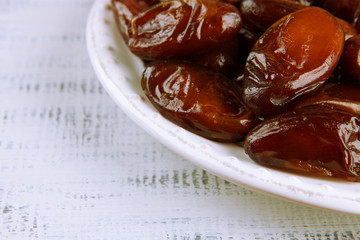 Dried dates on plate on wooden background