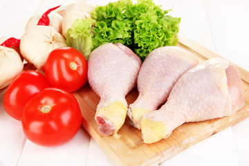 Raw chicken legs on wooden board close up