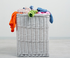 Full laundry basket  on wooden floor on gray background