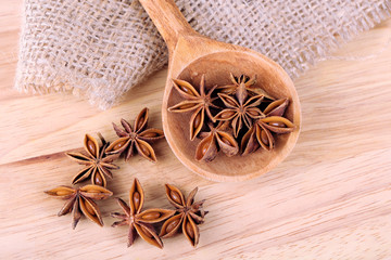 Star anise in wooden spoon, on wooden background
