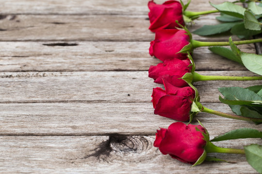 Five red roses on wooden background, selective focus