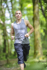Young man running in the woods listening music