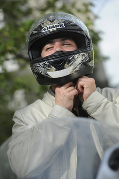 Young man with motorcycle putting the helmet