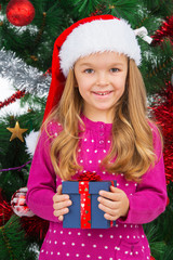 Beautiful blond girl in Santa hat smiling on camera.