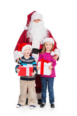 Old Santa Claus hugging little boy and girl with presents