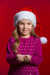 Little beautiful blond girl in red Santa hat holding snow.