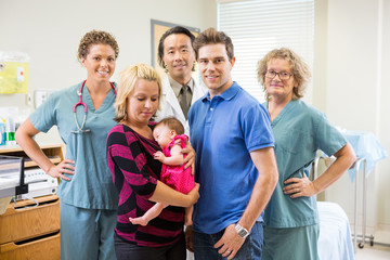 Medical Team With Newborn Baby Girl And Parents In Hospital