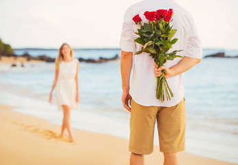 Romantic Young Couple in Love, Man holding surprise bouquet of r