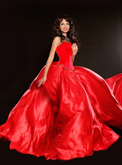 Beautiful brunette wearing in blowing red dress isolated on blac