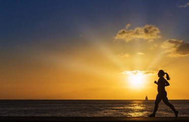 Silhouette women jogging on the beach at sunset