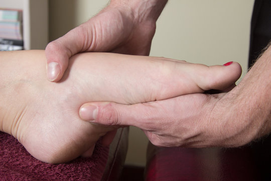 Chiropractor massage the patient bridge of foot