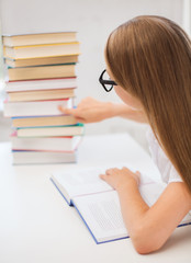 little student girl in eyeglasses with many books