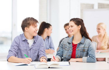 two teenagers with notebooks and book at school
