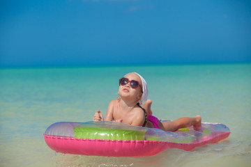 Little cute girl relax on pink air-bed in warm sea