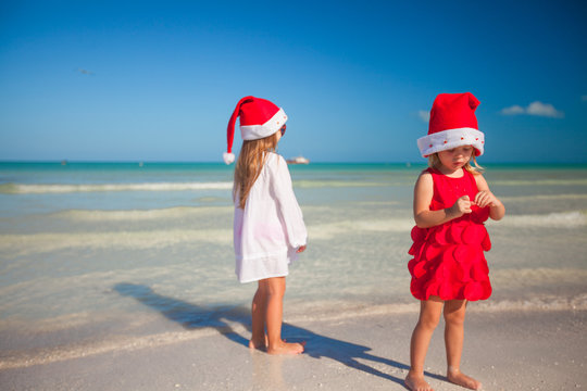 Little cute girls in Christmas hats on beach