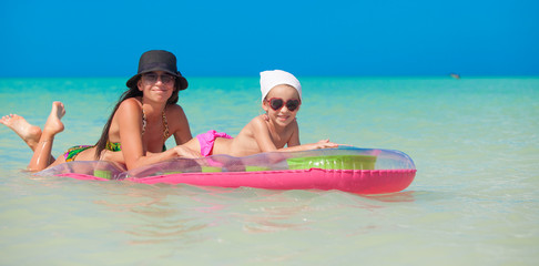 Little girl with young mother on an air mattress in the sea