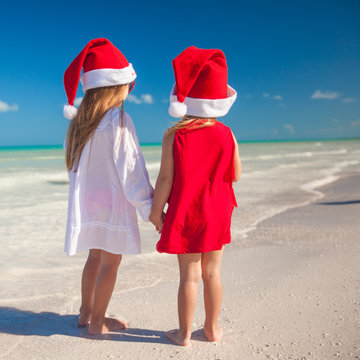 Little cute girls in Christmas hats on the exotic beach
