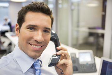 Portrait of smiling businessman at phone in office