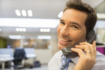 Portrait of smiling businessman at phone in office