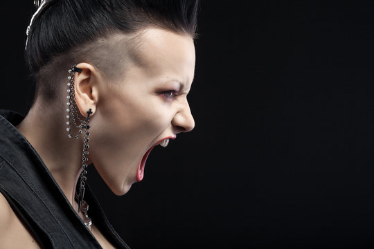 angry young woman screaming isolated on black background with co