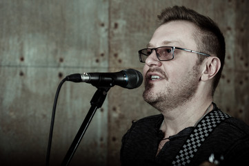 Naklejka premium Man singing to microphone in dark