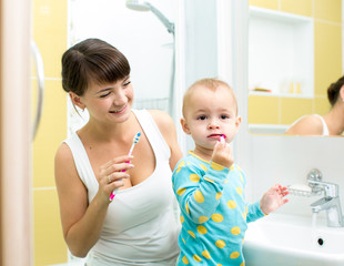 mother and baby brushing teeth in bathroom