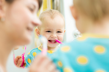 Obraz na płótnie Canvas mother teaches baby brushing teeth