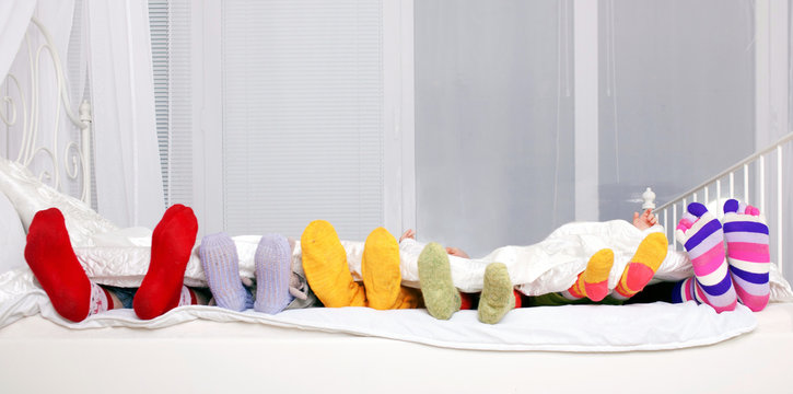 Happy Family In Colorful Socks On White Bed.