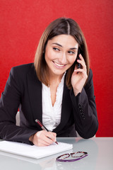 Young woman on the phone work desk smiling