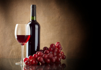 Bottle of wine and a bunch of red grapes - obrazy, fototapety, plakaty