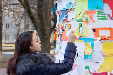 Woman tearing off a contact number on a notice