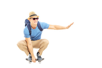 Smiling male student with backpack skating on a skate board