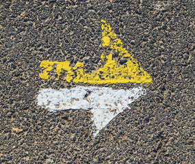 arrow in yellow and white on a paveway for orientation