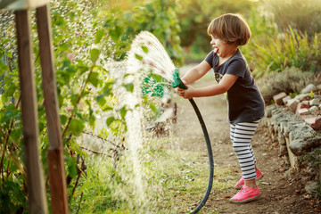 Little happy girl watering garden