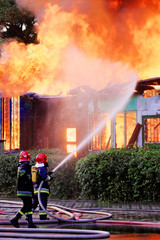 Firemen in action on burning ruins of building