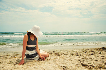 Nostalgic woman with hat standing on the beach