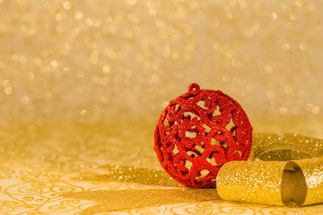 Red Christmas ornament and golden ribbon on shiny background
