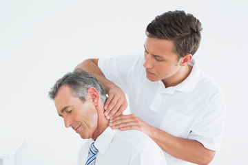Male chiropractor massaging patients neck