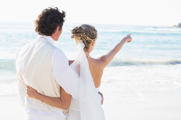 Fototapeta na wymiar Newlyweds standing by the sea with wife pointing