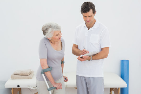 Therapist discussing reports with a disabled senior patient