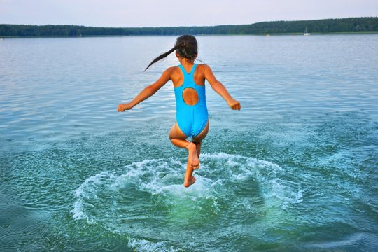 Girl leaping into lake, aged 10 years