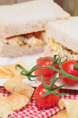 Fresh egg and tomato on white sandwich in rustic kitchen setting