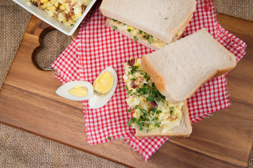 Fresh egg and bacn on white sandwich in rustic kitchen setting