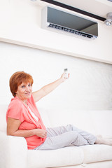 Woman holding a remote control air conditioner