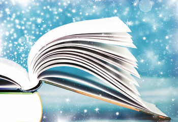 Open book with magic light and falling stars