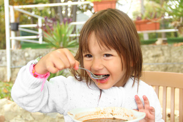 Little girl eating vegetarian soup outdoors in summer