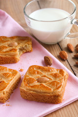 Almond biscuits closeup on pink tablecloth with a cup of milk
