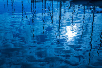 Blue water reflection of sailboats boats poles in waves