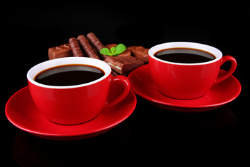 Red cups of strong coffee and chocolate bars isolated on black
